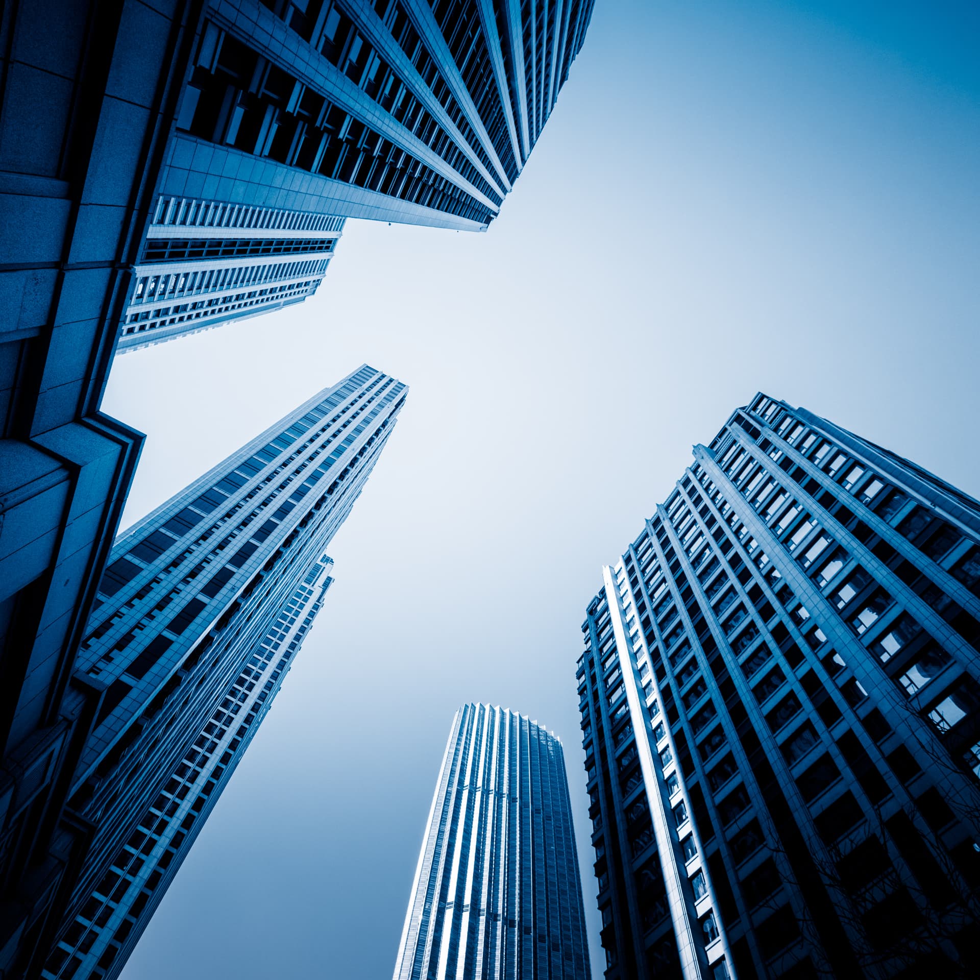 Modern skyscrapers rising into a clear blue sky, seen from a low angle
